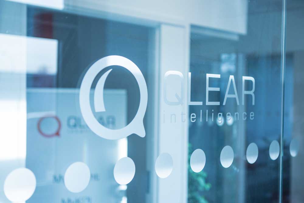 Qlears logotyp på en transparent glasvägg